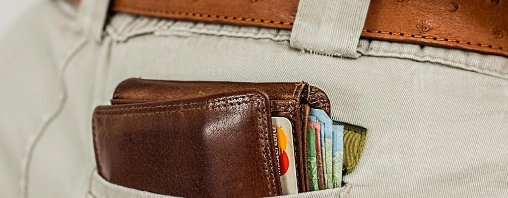 Billetera llena de dinero en un bolsillo trasero de un pantalón
